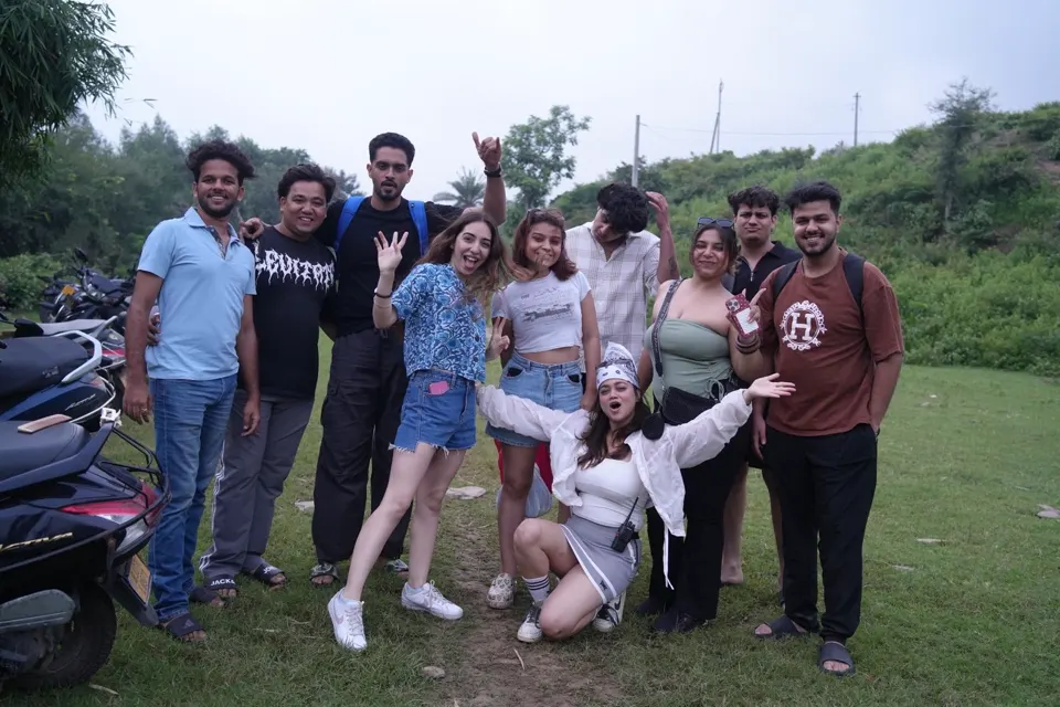 Travellers laughing mid-pose on green hills under a soft grey sky