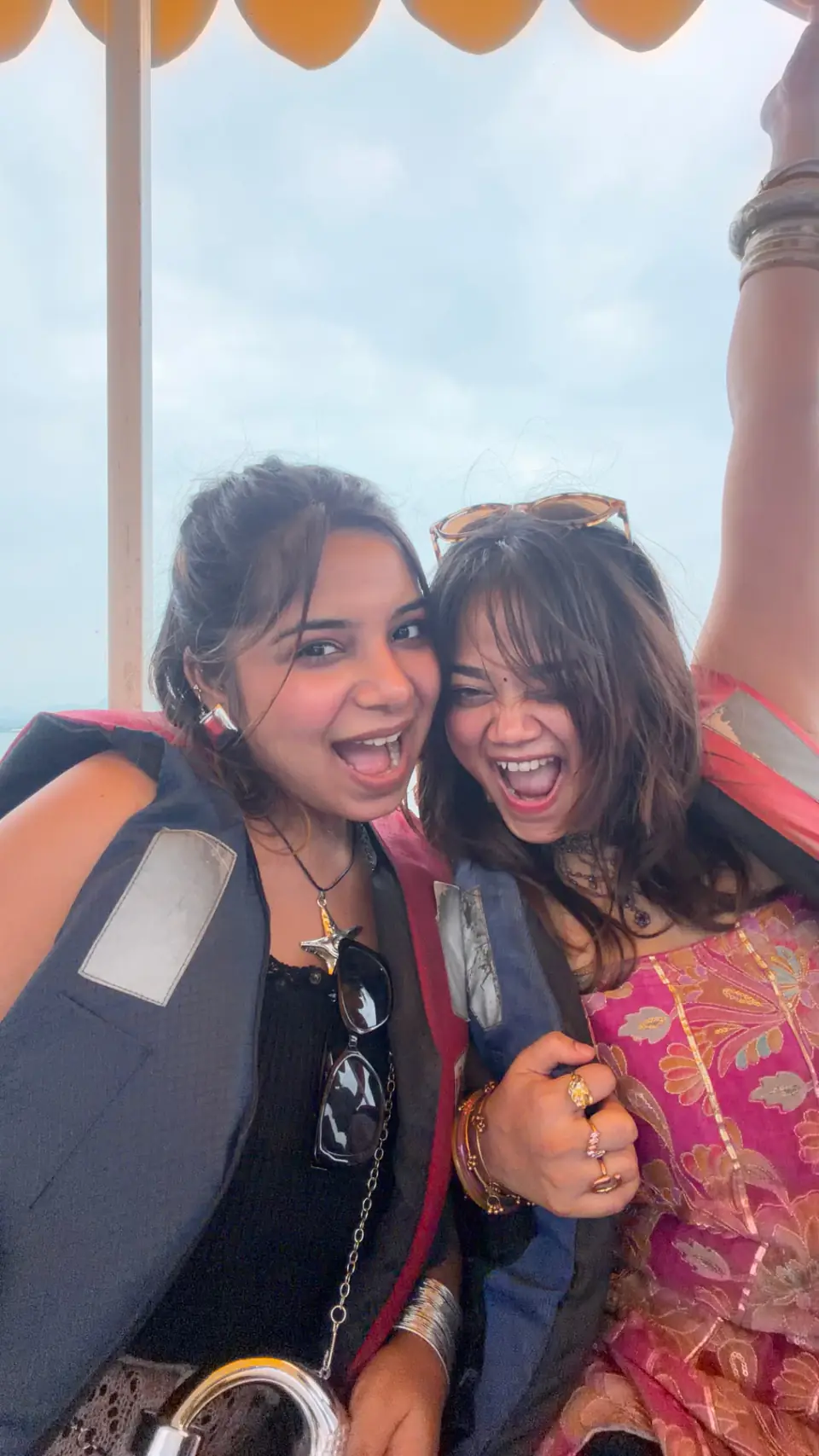 Two travellers laughing on a boat with the lake behind them
